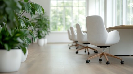 A row of white chairs is positioned next to large windows, surrounded by an array of green plants. The modern office setting creates a calm and serene working environment.