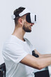 © BullRun - Side view of cheerful male trying virtual reality headset glasses for testing VR environment, successful man in modern advanced equipment enjoying time for cyberspace using stylus pen and touch pad