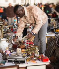 Wall Mural - Man looks at second-hand items at a flea market