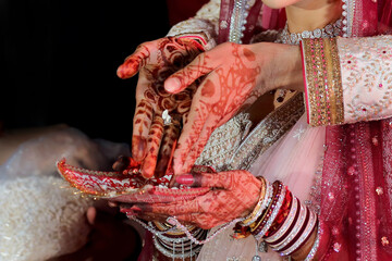 a beautiful bride adorned with intricate mehendi designs, delicately performing a traditional indian