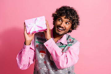 Canvas Print - Portrait of nice young man hold gift box look empty space wear x-mas new year vest isolated on pink color background