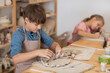 © ulza - kids works with clay makes  ceramic plate in pottery school.  Children arts a crafts class in workshop.