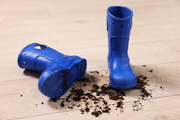 Canvas Print - Rubber boots with mud on wooden floor