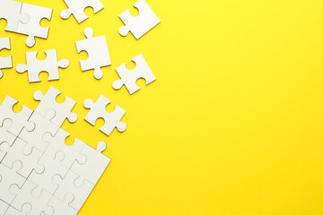 Wall Mural - White puzzle pieces on yellow background, top view. Space for text