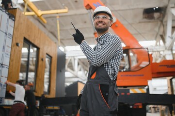 Wall Mural - Foreman manages the loading of a prefabricated modular house to truck using walkie talkie