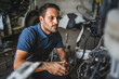 © Miljan Živković - Car mechanic work on a car engine in a garage wearing blue shirt