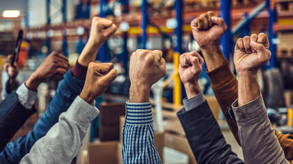 Wall Mural - Workers In A Warehouse Raising Their Fists Together, Symbolizing Strength And Teamwork, Fists Raised In Solidarity In A Warehouse