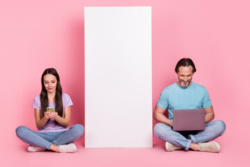 Sticker - Full length portrait of two nice cheerful people sit floor use telephone wireless netbook isolated on pink color background