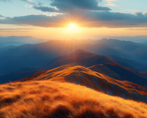 Landscape of majestic mountain ranges at sunrise, with golden sunlight casting soft rays over distant hills and valleys. The foreground consists of a grassy ridge covered in golden autumn hues.