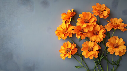 A bouquet of orange flowers is placed on a grey background