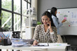 © amnaj - Asian businesswoman smiling while multitasking at desk with charts and graphs, another woman working in background