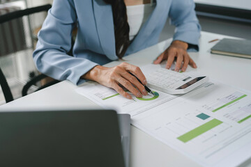 Wall Mural - Businesswoman is analyzing financial data and using a calculator to review company profits, expenses, and growth potential