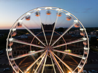 Large colorful Ferris wheel in city center. Aerial drone view on Colorful Ferris wheel spinning in the city center Dabrowa Gornicza Poland. Colorful Ferris wheel From a bird's eye view drone at night.