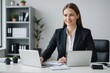 © ThomasLENNE - Businesswoman with laptop sitting at desk in office