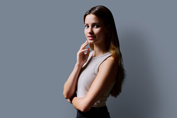 Wall Mural - Portrait of beautiful young girl with long red hair looking at camera on grey background