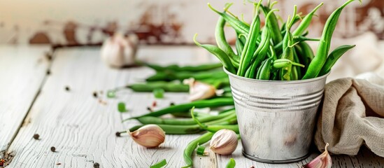 Wall Mural - Green beans in an aluminum cup along with a napkin and garlic on a white wooden table Autumn recipes Copy space