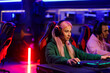 © Zamrznuti tonovi - Professional gamer girl with headset playing cybergames in internet cafe