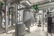 © alhim - An interior shot of a building's mechanical room. Several large pipes are visible, along with a large water heater and other mechanical equipment. The room is brightly lit, with a concrete floor.