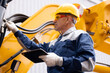 © Parilov - Machinery tractor mechanic with tablet computer checks hydraulic piston hose system equipment on excavator. Concept industry truck maintenance