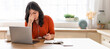 © Prostock-studio - Arabic woman with long hair sits at a desk, looking stressed while struggling to work on her laptop. She holds her glasses, resting her forehead with one hand in a well-lit, inviting workspace.