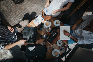 Wall Mural - Business workers collaborating together in a coffee bar, brainstorming ideas, and sharing knowledge for solutions while working remotely.