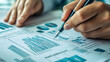 © kwangze - Close-up of a person analyzing financial data on paper, highlighting trends and statistics with a pen.