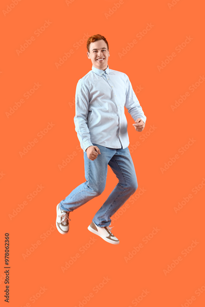 Jumping young man on orange background