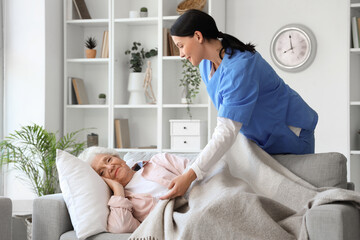 Wall Mural - Female nurse caring about lying senior woman at home