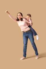 Wall Mural - Beautiful mother with her cute little daughter having fun together on brown background