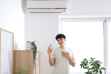 Canvas Print - Young man switching  on air conditioner at home