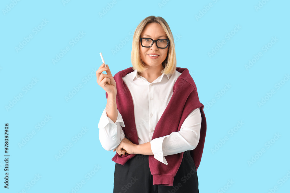 Mature female math teacher holding chalk on blue background