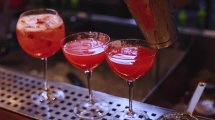 Wall Mural - Bartender working, beautiful row line of different coloured liquor alcohol cocktails on a party in a bar catering banquet on event, barman mixing drinks and beverages in club in slow motion
