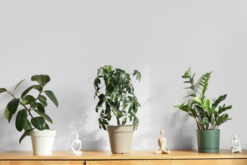 Wall Mural - Green plants with statuettes on commode near light wall