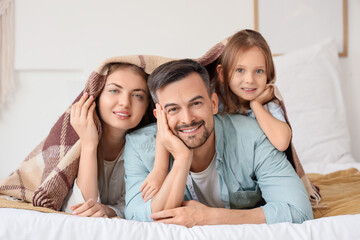 Sticker - Little girl and her parents lying under warm plaid in bedroom