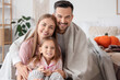 © Pixel-Shot - Little girl and her parents with warm plaids hugging in bedroom