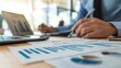 © Juan - Business professional reviewing financial charts at a desk