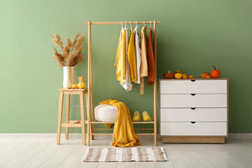 interior of hallway with autumn clothes, drawers and pumpkins