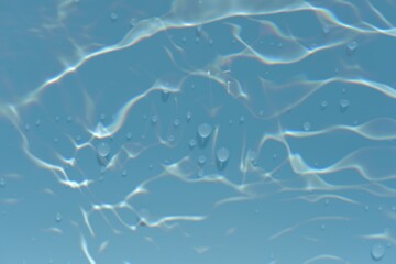 Blue water with ripples on the surface. Defocus blurred transparent blue colored clear calm water surface texture with splashes and bubbles. Water waves with shining pattern texture background.