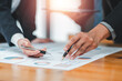 © Satori Studio - Close-up of business professionals discussing financial charts and graphs during a meeting, highlighting teamwork and data analysis.