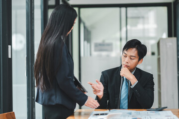 professional business meeting in a modern office with two asian colleagues discussing documents and 