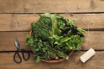 Wall Mural - Different aromatic herbs in wicker basket, thread and scissors on wooden table, flat lay