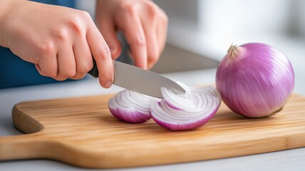 A close-up of hands slicing a red onion on a wooden cutting board, showcasing fresh ingredients for cooking.