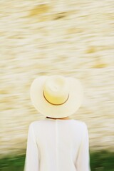 Aufkleber - Abstract Blurred Person with Sun Hat Against Symmetrical Beige Stone Wall in Warm Tones