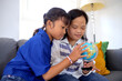 © Gatot - Young Down Syndrome Girl Studying World Map With Her Friend at Home