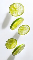 Five lime slices falling against a white background.