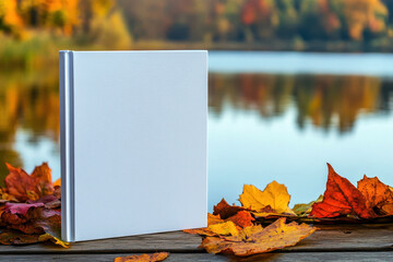 Wall Mural - a white book for mockup on wooden table, top view next to yellow autumn maple leaf. Mockup, empty space, place for text.