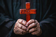 © Valeriia - African-American hands of religious priest holding big red wooden cross. Religion, peace, faith in God and Lord and optimism