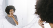 © JordaanExams/peopleimages.com - Wipe, mirror and girl with face tissue, cleanser or morning routine in home, bathroom or house. Beauty, makeup removal or afro woman with facial skincare, reflection or cosmetic treatment application