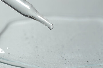 Poster - Dripping cosmetic serum from pipette on light background, closeup