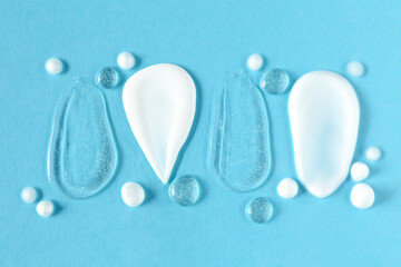 Sticker - Smears of different cosmetic products on light blue background, flat lay